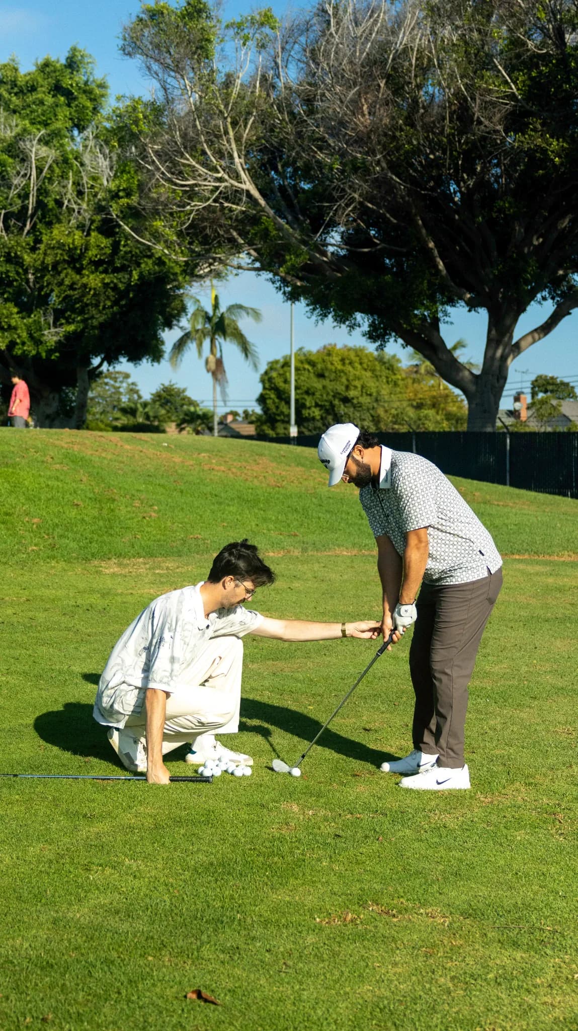 Harrison Cody Christie guiding a golfer's grip during a lesson